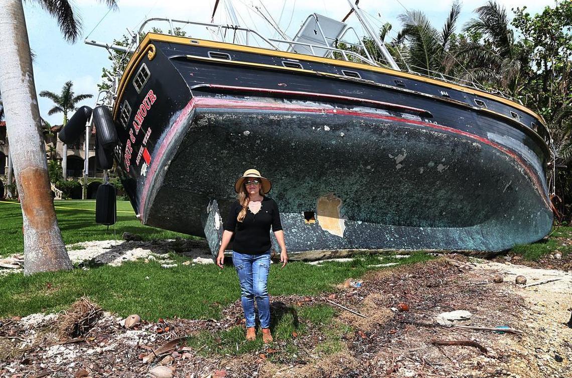 Jessica Ivler, a Coconut Grove resident, stands next to one of the boats that were washed ashore into her backyard.