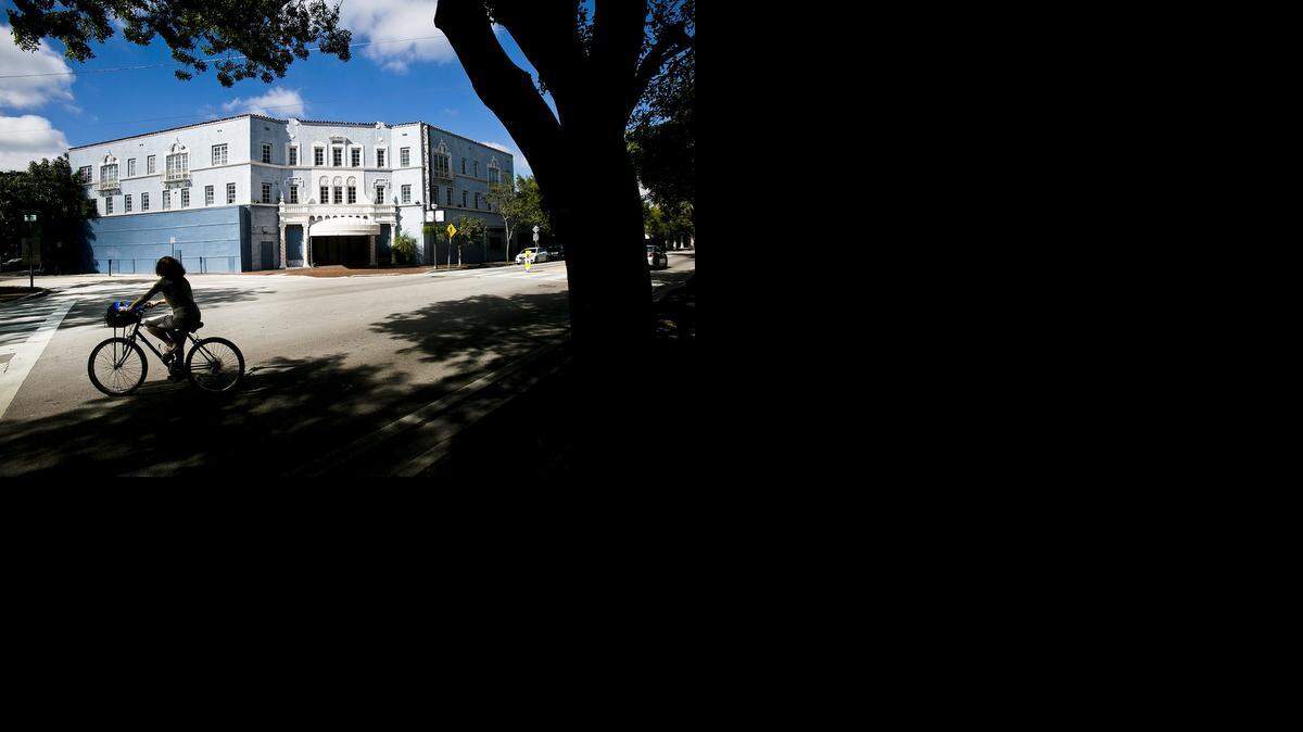 
A woman rides her bike past the vacant Coconut Grove Playhouse. Some significant development plans and property ownership changes are currently taking place in Coconut Grove.
