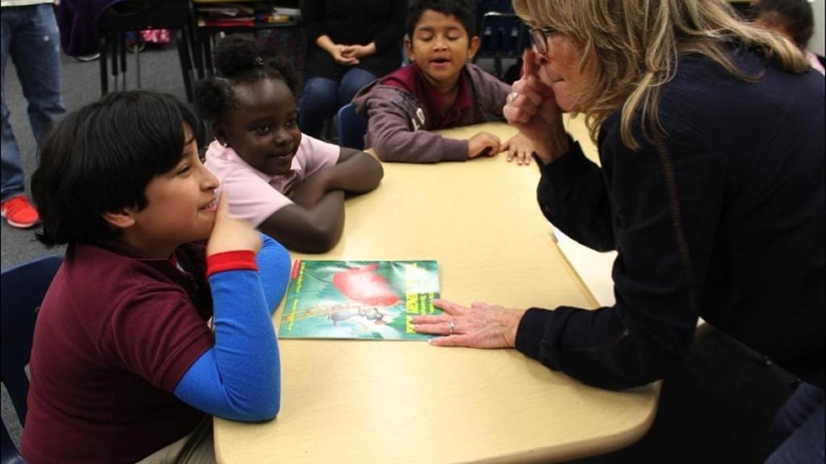 Volunteer storyteller Patty Pero signs to deaf students Zahir Brenes, Alexis Simmons and Jesser Ferrary at Auburndale Elementary School in Little Havana at an event hosted by the South Florida Deaf Recreation Association.