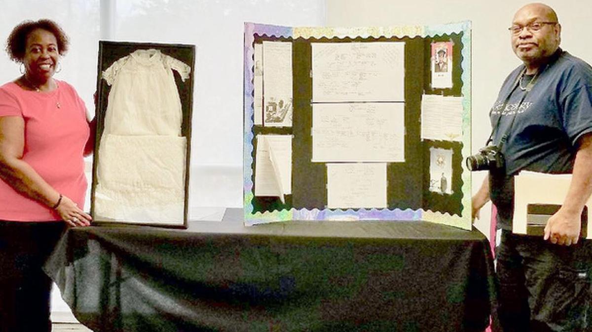 Patricia Jennings Braynon with maternal grandmother Genevieve Ward-Franks’ 1896 christening gown worn by Braynon and other family members. It has been preserved for display at descendant’s baptisms. Marvin Elliott Ellis displays his international family tree containing genealogical information of his paternal lineage in 1790 in Wilkes County, Georgia, and maternal lineage in 1799 St. Croix, Danish Virgin Islands.