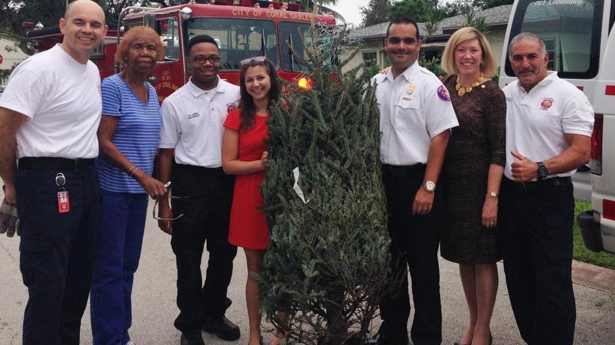 Giving away free Christmas trees are, from left: Coral Gables Fire Department Lt. David Perez; Edwina Prime, Lola B. Walker Homeowners Association president; Gables Fire Lt. Xavier Jones; Mary Snow, Gables Community Foundation director; Gables Deputy Fire Chief Marcos de la Rosa; Gables Commissioner Jeannett Slesnick; and Gables Fire Capt. Jesus Acevedo.