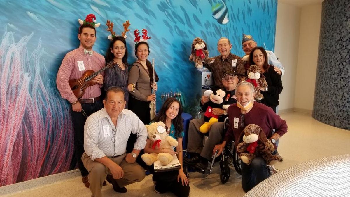 Volunteers with the Hearing Research Institute and Post #243 of the Jewish War Veterans USA visited children hospitalized during the holidays at Holtz Children’s Hospital and Nicklaus Children’s Hospital. From left, in front, are Luis La Lama, Child Life Specialist Beke Pickard, Ainslee Ferdie and Marvin Dorn. From left, in back, are Graig Gamendia, Christina La Lama, Jennifer La Lama, Robert Pickard, David Magidson and Susan Pickard.