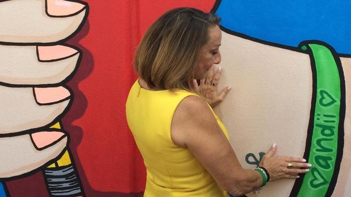 
Miami-Dade School Board member Susie Castillo with a mural honoring her daughter Andrea, who died at 21 in a 2012 car accident. The artwork, by Tony Mendoza, also honors Raphael Acevedo, who died at 17 in 2014. Both attended Ronald W. Reagan/Doral Senior High School.
