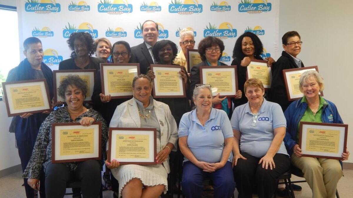 A group of active adults hold up their diplomas after graduating from the office skills training program on March 29 at Cutler Bay Town Hall.