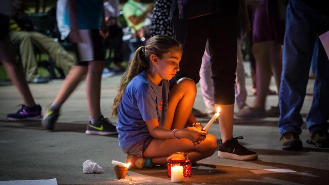 Nikita Santillan sits, surrounded by candles, at Bayfront Park, in Miami, Aug. 13, 2017, during a vigil being held in honor of the victims of violence at a white nationalist rally in Charlottesville, VA.