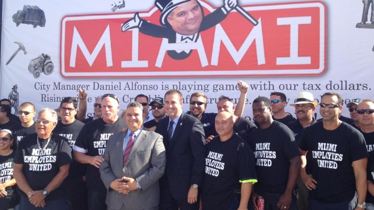 Miami City Manager Daniel Alfonso in October 2014 (grey suit) next to police union president Javier Ortiz ahead of a budget hearing. Miami’s employee unions say Alfonso skews numbers to make the city appear as if it has less money.