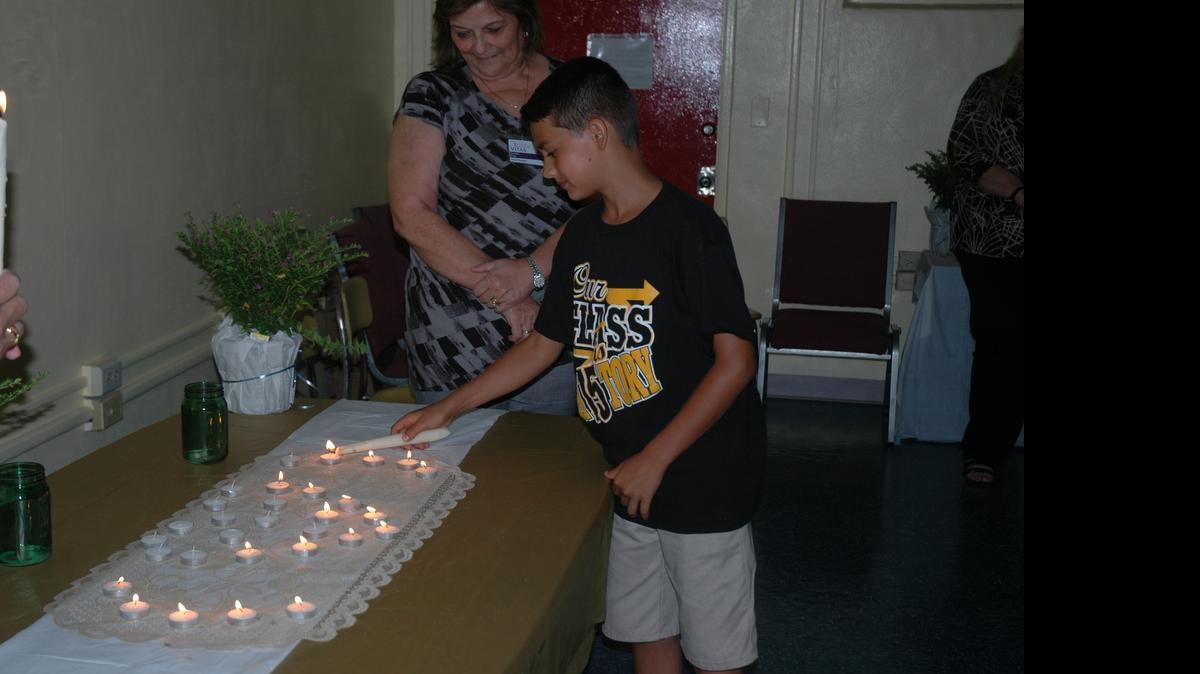 
Jared Chartrand lights a candle in memory of a loved one as VITAS General Manager Laurie Fitz looks on.
