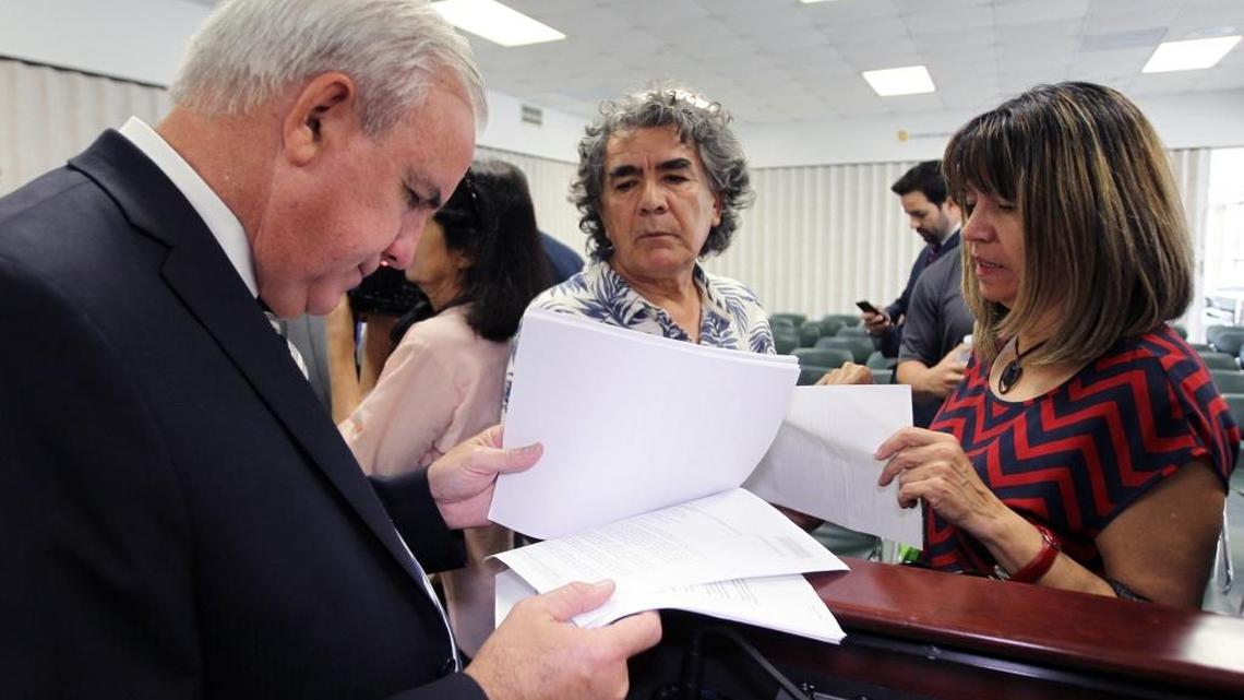 Miami-Dade Mayor Carlos Giménez speaks with Luz Moscoso and Ruben Gallardo, condominium owners who attended the meeting at county police headquarters .