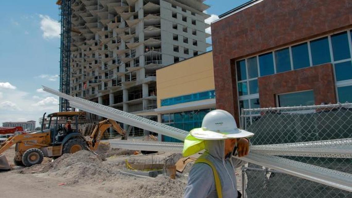 A construction worker carries building materials at the construction site of Downtown Doral.