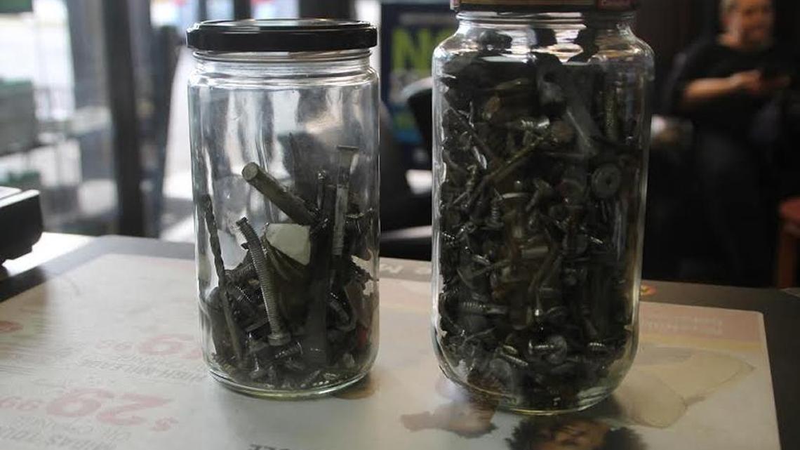Two jars collect nails and other debris taken from flat tires at the Midas shop on 2175 NE Second Ave.