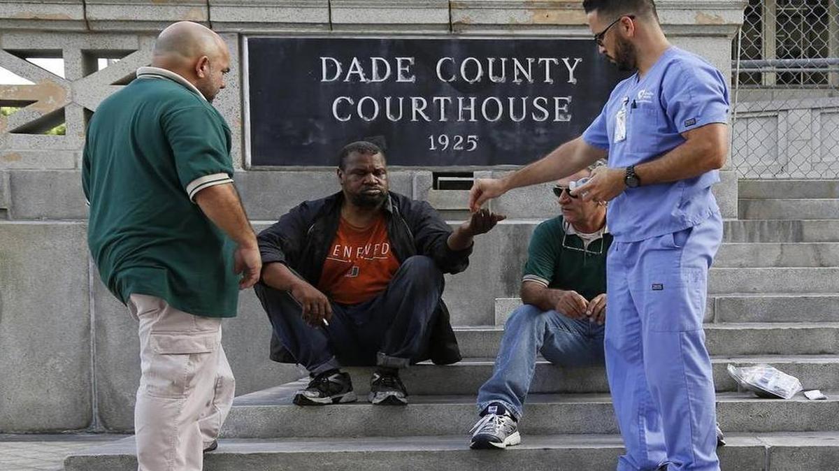 
Members of the Lazarus Project, Ivan Romero, housing supervisor, Lazaro Trueba, program administrator, and Adrian Mesa, psychiatric advance registered nurse practitioner, right, talk with Alec Johnson, a homeless man, as he receives his medication on June 7, 2015.
