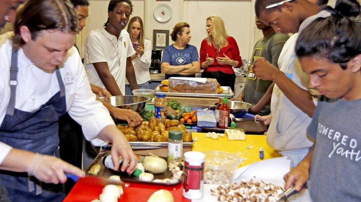Empowered Youth program founder Colleen Adams, in background with long blonde hair, in the kitchen at Trinity Church in Miami, November 3, 2015.