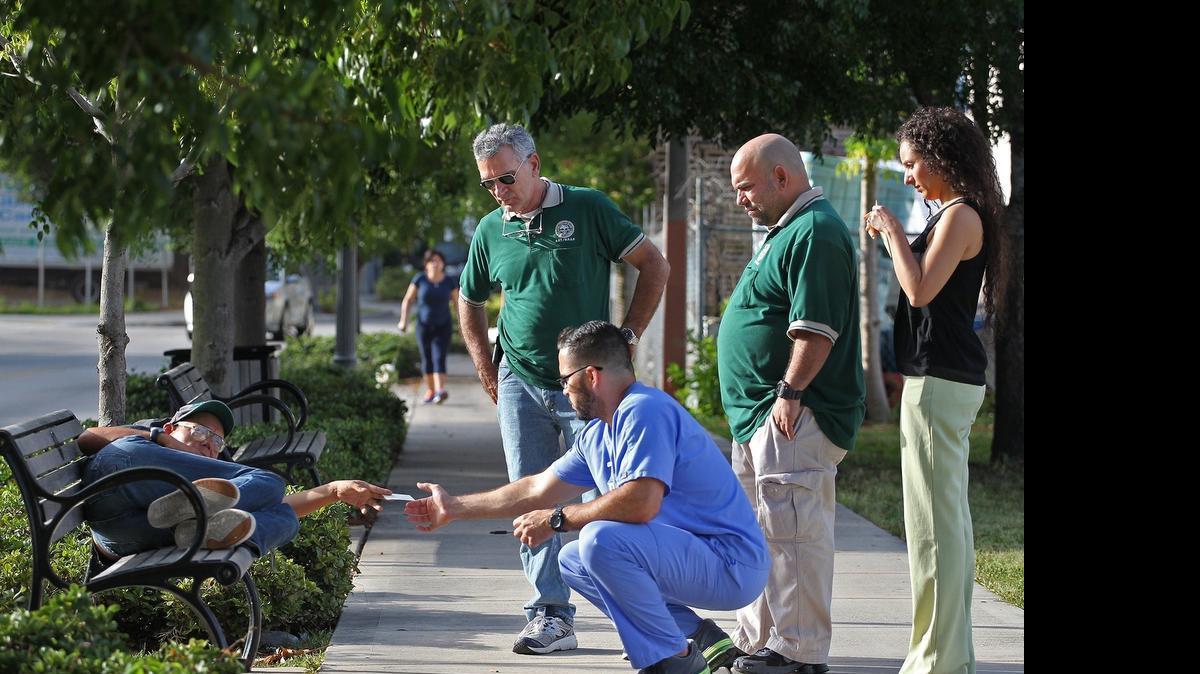 
Angela Piper, left on bench, shows her identification to Adrian Mesa, psychiatric advance registered nurse practitioner, kneeling, as Lazarus Project team members, Lazaro Trueba, Ivan Romero, and Claudia Basso, right, canvas the streets of downtown Miami to administer psychiatric, social, and heath treatments for their Miami's chronic homelessness clients on Tuesday, June 7, 2015. For more than six months, a team of four has headed out into the streets of downtown Miami area to serve medical and psychiatric treatments to the chronic homelessness clients.
