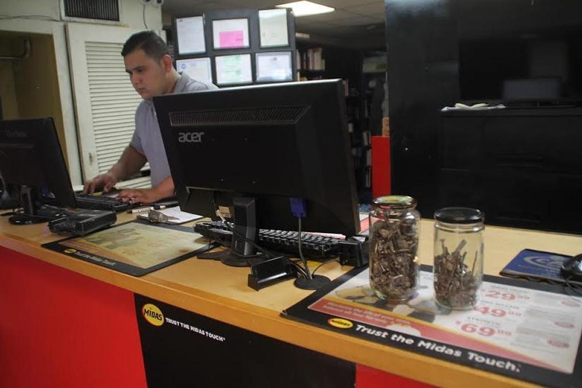 Midas Service Advisor David Gonzalez works near jars holding nails and debris taken from flat tires at the Midas shop at 2175 NE Second Ave.