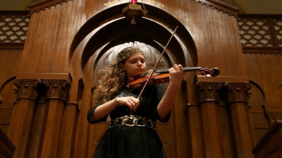 Biana Pinchuk plays the violin as a crowd gathers to commemorate Kristallnacht at Temple Israel of Greater Miami on Sunday, Nov. 6, 2016, in Miami.