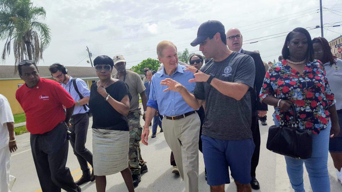 Miami Mayor Francis Suarez, right in hat, talks with Sen. Bill Nelson, center, about how gun violence has affected Liberty City.