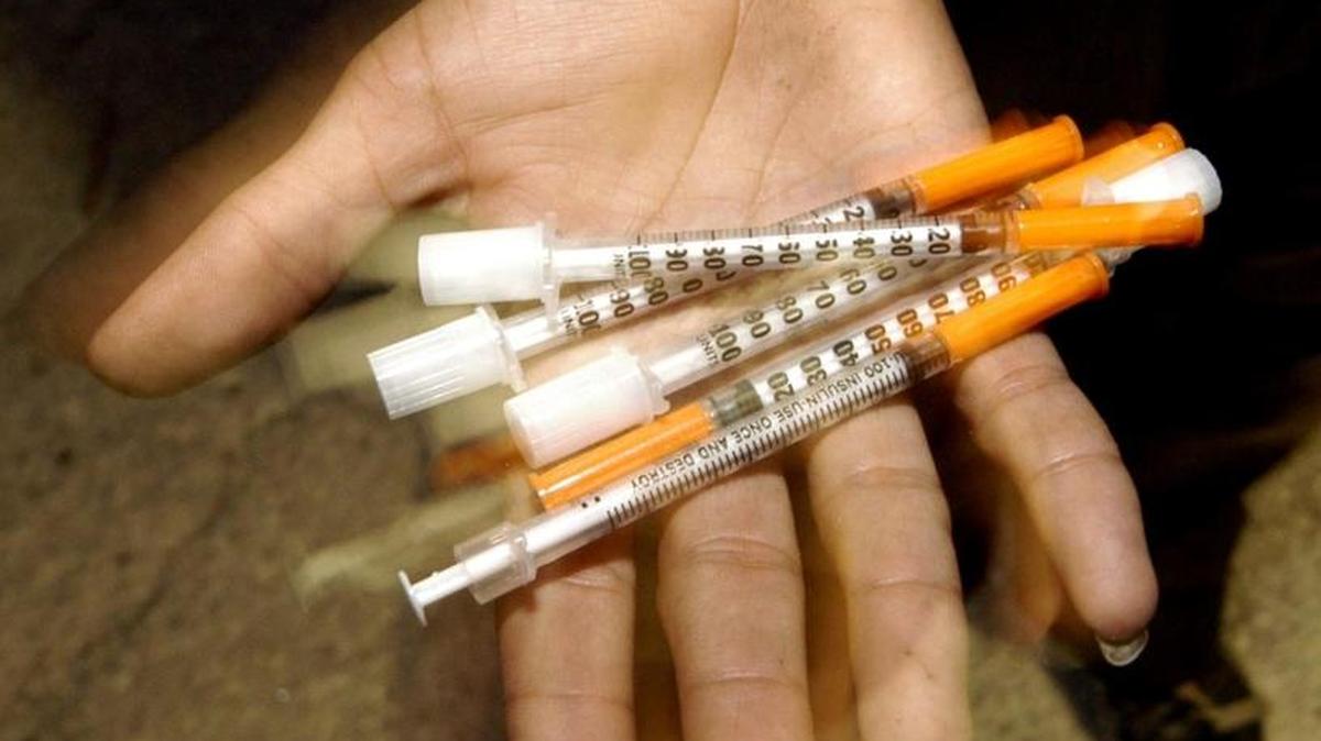 Street addict shows his stash of needles in the Overtown section of Miami.
