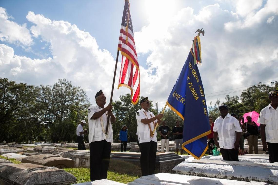 Veterans William Starlind and John Pratt hold flags during a Veterans Day remembrance in 2017 at the historic Charlotte Jane Memorial Cemetery in historically Black West Coconut Grove.