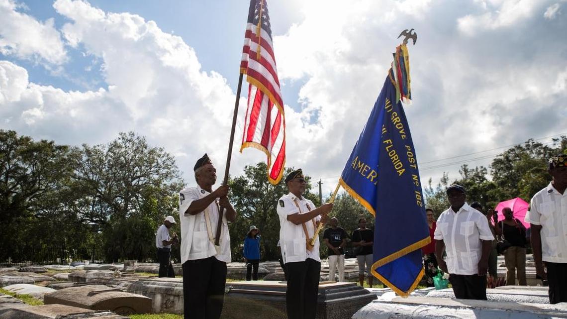 Veterans William Starlind and John Pratt hold flags during a Veterans Day remembrance at the historic Charlotte Jane Memorial Cemetery in historically Black West Coconut Grove in 2017.
