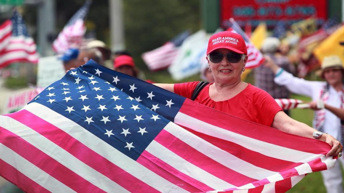 Nancy Leon Garcia holds an American flag during a rally outside Tropical Park on Saturday to support President Donald Trump and his likely changes to U.S.-Cuba policy.