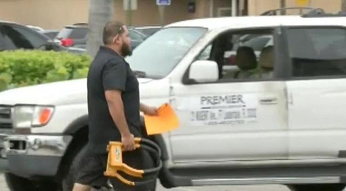 An employee of Premier Booting carries a metal boot used to immobilize a parked car.
