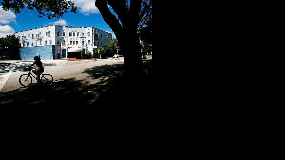 
A woman rides her bike past the vacant Coconut Grove Playhouse
