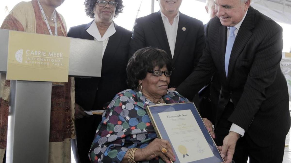 En el sentido de las agujas del reloj, desde la parte superior a la izquierda, la comisionada del condado Barbara Jordan; Lucia Davis-Raiford, hija de Carrie Meek y directora de Servicios Sociales del condado; Esteban Bovo, presidente de la Comisión del Condado, y el alcalde de Miami-Dade, Carlos Giménez, entregan a Carrie Meek una proclama durante la ceremonia de colocación de la primera piedra del nuevo almacén de Amazon de la Carrie Meek Foundation en el aeropuerto de Opa-locka.