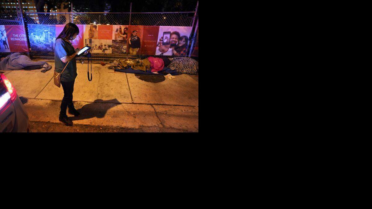 
Janay Guerrero, with the City of Miami Homeless Program, counts homeless people sleeping on the sidewalk in front of the future Miami Worldcenter downtown on Jan. 22 during the Homeless Trust's annual count of the homeless population.
