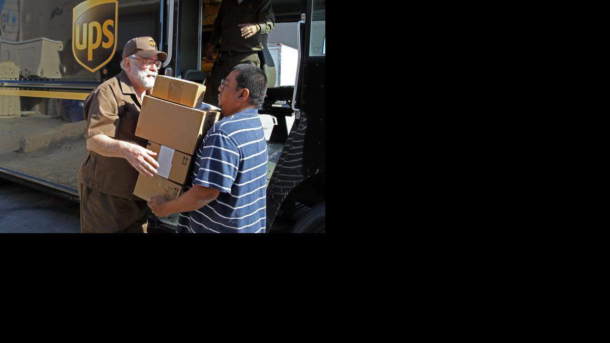 
Miami Herald reporter Glenn Garvin (left) hands over a delivery to Danny Lopez from American Cargo Logistics Inc. Garvin works on a UPS delivery truck with UPS's Manuel "Camilo" Jimenez for a first-person story on what the job is like at the height of the holiday season Tuesday Dec. 16, 2014. 
