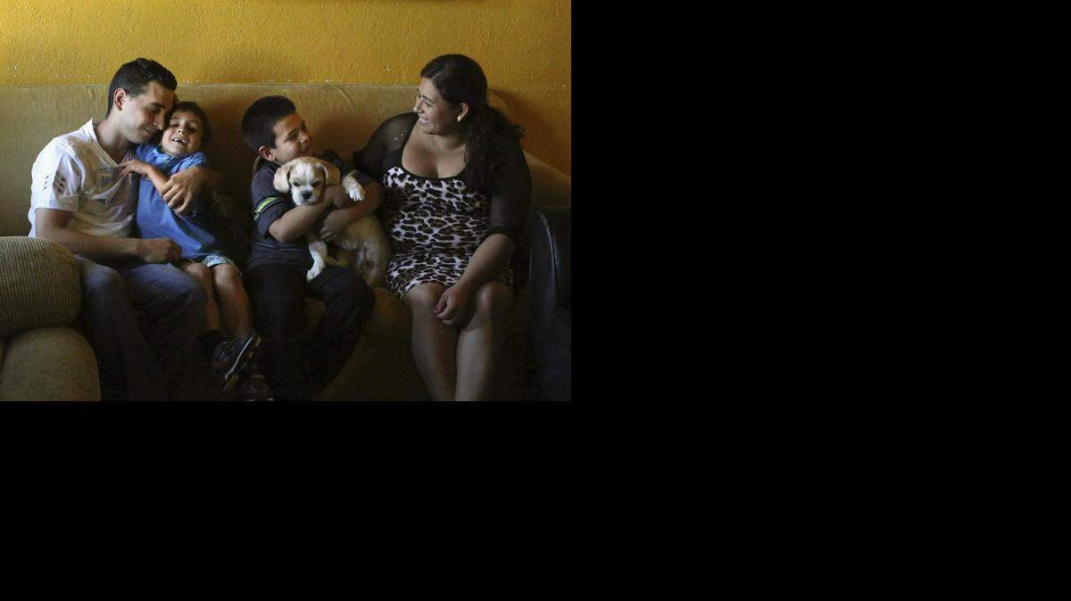 
GRATITUDE: Joel Diaz and Belkis Johana Mairena share happy moments with their sons Emanuel Diaz-Mairena, 6, left center, and Richard Diaz-Mairena, 8, who holds family dog, Jack, on Thursday, Oct. 30, 2014 in their rented home in Miami.
In July, Emanuel was hit by a car while playing ball in the street with Richard and friends. Emanuel suffered traumatic brain injury, was in a six-week coma, and had a seizure. He has recovered more than his doctors expected. The family is thankful to have their sons with them and for the doctors at Jackson Memorial Hospital.
