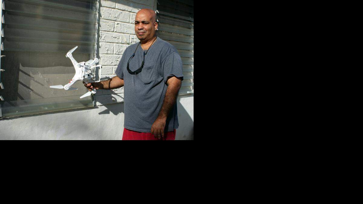 
MYSTERY DRONE: Andrus Baksh holds the high-tech drone that crashed into his Hialeah home, breaking four panes of his jalousie window.
