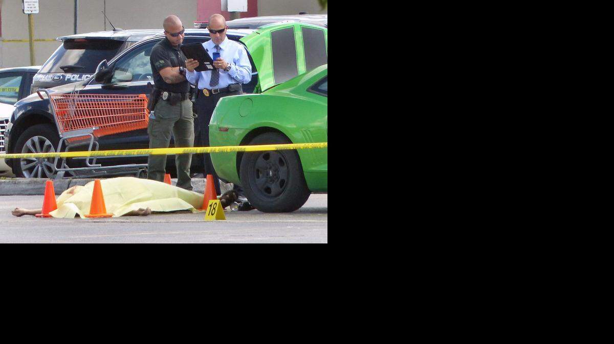 
SHOOTING SCENE: Hialeah police investigators stand over the body of a man killed in an armed confrontation at the Westland Commons shopping mall. 
