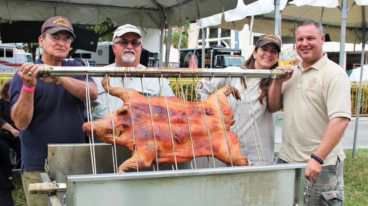 From left to right, Sandy Valladares, Nelson Serpa, Frances Valladares, and Miami-Dade Police Department's Tony Valladares, show their 43-pound roasted pig during the inaugural "Pig Cook Off." The event was held at Hialeah Park Racing and Casino on Sunday to benefit a local boy who was recently diagnosed with leukemia.