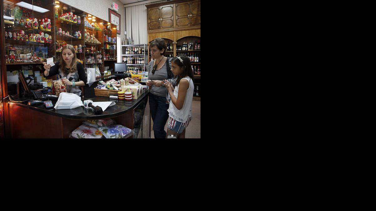 
Nadia, center, and her daughter Mariam pay Juliana Romanova for the Russian products they bought at Marky's Caviar Russian Store in Miami on Tuesday, Nov. 11, 2014.
