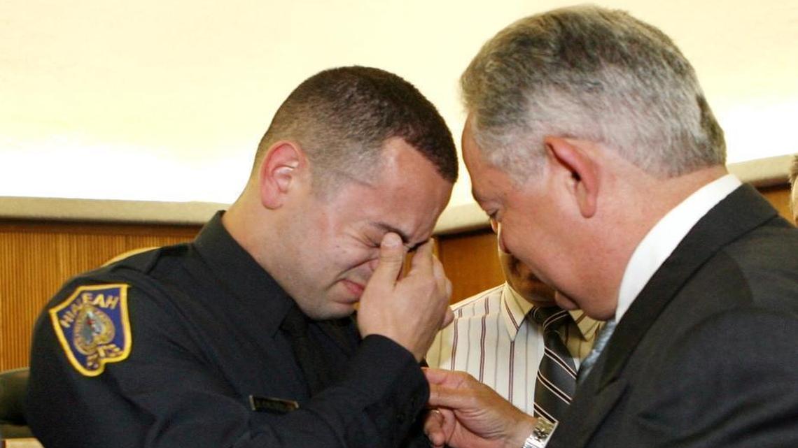 In this file photo from 2006, new Hialeah police officer Raul Castellon Jr. is overwhelmed with emotion as his father Raul Sr. pins his new badge during a swearing-in ceremony.