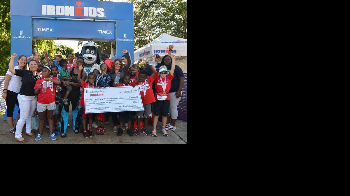 
Candy Sicle, director, UnitedHealthcare of Florida, (front, sunglasses) presents a $3,000 cheque to Tina Brown, executive director, Overtown Youth Center of Miami, (fifth from left holding baby) to support the center’s healthy living programs at the UnitedHealthcare IRONKIDS Miami Fun Run at Bayfront Park.
