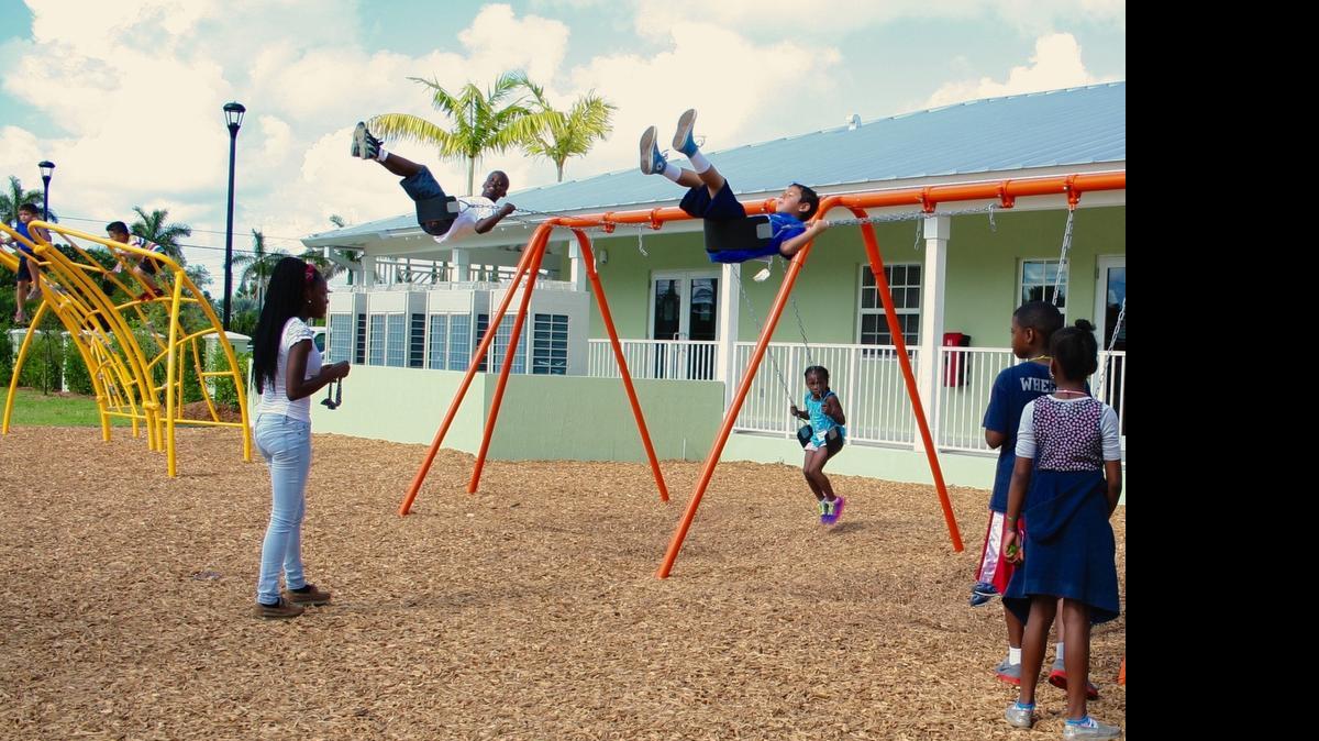 
Patricia Jeudy, left, watches over as James Green, Geniziz Desir and Angel Guevera play on the swings in the new Branches playground in Florida City. Jeudy, who has grown up in the Branches afterschool and summer programs, now helps up as a camp guide for the younger kids.
