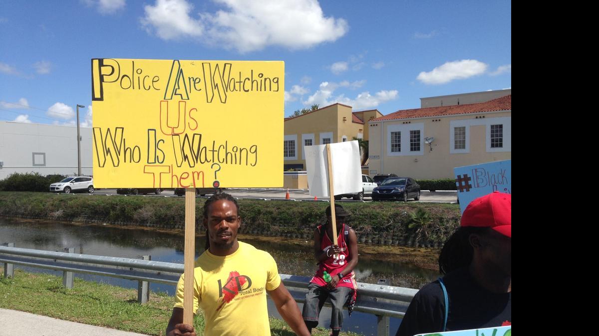 
Kevin Bove, a personal trainer in North Miami Beach, holds a sign in protest of John Rivera, president of Miami-Dade’s police union. Rivera claimed the county’s mayor wanted body cameras for police in order to gain favor with black voters.
