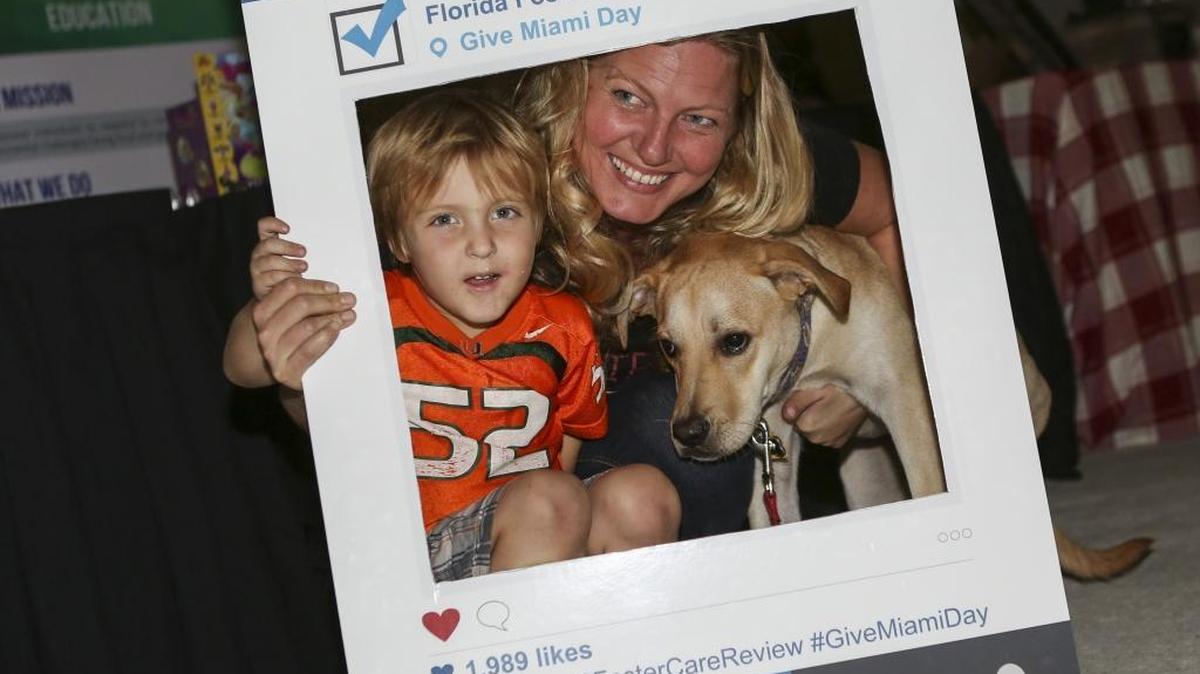 Virginia Emmons McNaught, Miles McNaught, then 4, and their rescue dog, Nelson, take a photo with an Instagram cutout during the Give Miami Day block party at Miami Dade College’s Wolfson Campus in downtown Miami on Thursday, Nov. 17, 2016. The block party was hosted by The Miami Foundation in conjunction with the Miami Book Fair.
