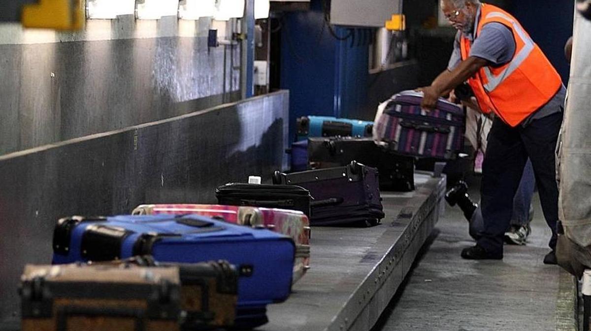 In this 2013 file photo, a baggage handler unloads luggage from an incoming flight at Miami International Airport.