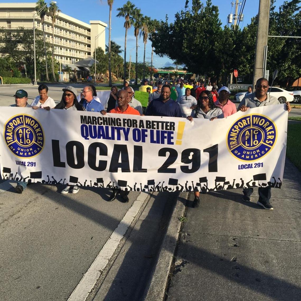 Miami-Dade’s transit union took the lead in Monday’s “transit march” between Cutler Bay and Palmetto Bay. Rep. Kionne McGhee, wearing an orange shirt, is at the center of the banner as the crowd headed toward U.S. 1.