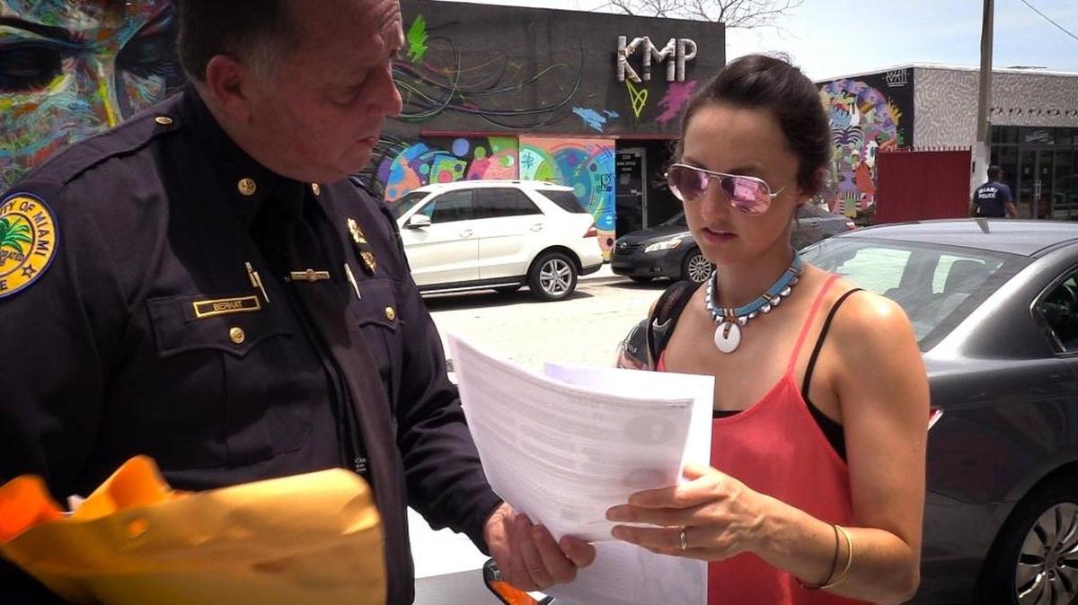 Miami Police Homeless Coordinator James Bernat gives a Zika prevention leaflet to a tourist in Wynwood earlier this month.