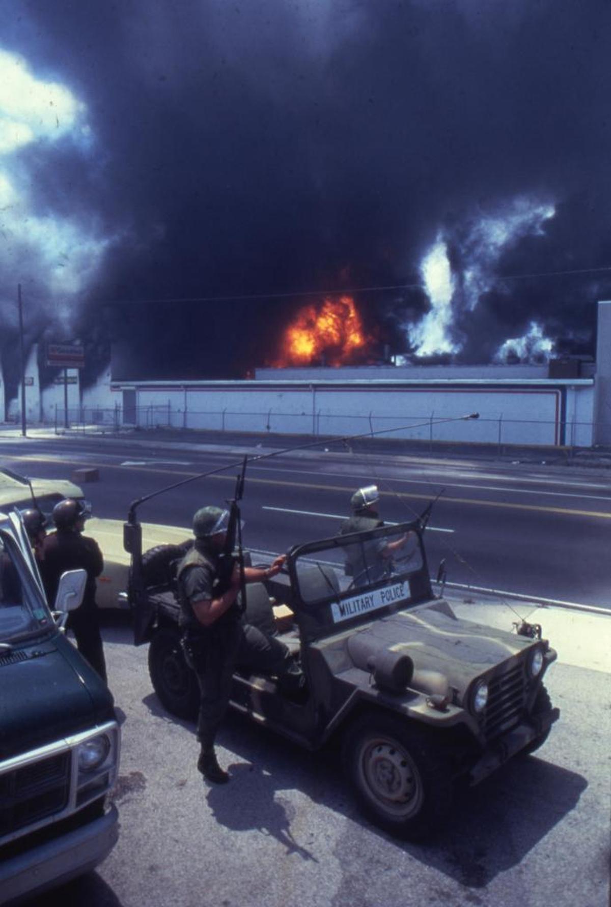 National Guardsmen take position across from burning Norton Tire Company on May 18, 1980. Black smoke from the building at Northwest 27th Avenue and 54th Street filled the city's sky.