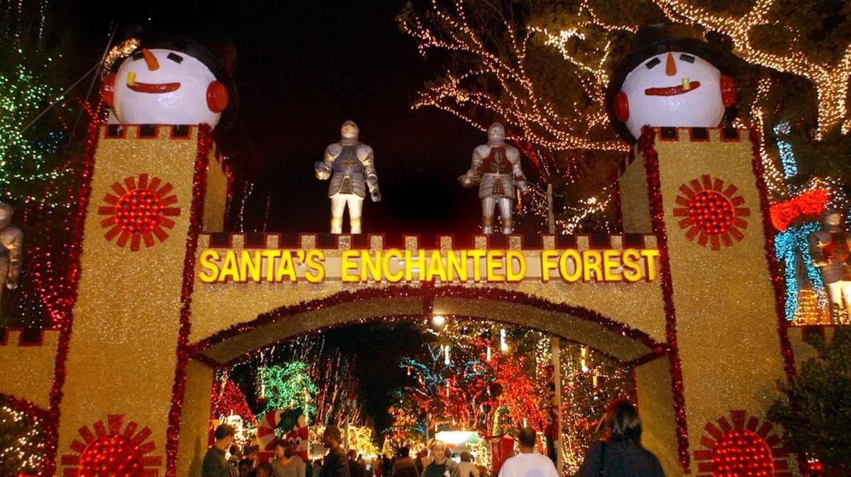 Visitors pass through the gates of Santa's Enchanted Forest, a holiday attraction featuring displays, rides, performers and a carnival in Miami on Wednesday evening, December 18, 2002.