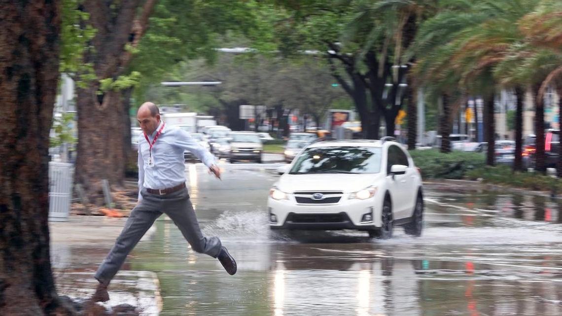 A pedestrian jumps over a flooded street on Miami’s Brickell Avenue as heavy rains come down hard on Oct. 5.