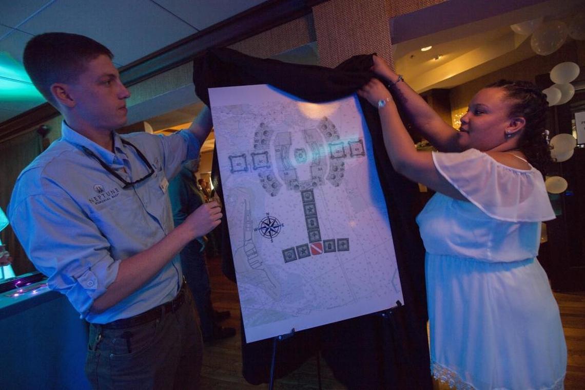 Ray Lowenstein, Neptune projects manager, and Nikita Stuart, Neptune office manager, uncover the new map at the Neptune Memorial Reef event to announce the enlargement of the underwater mausoleum three miles off Key Biscayne.