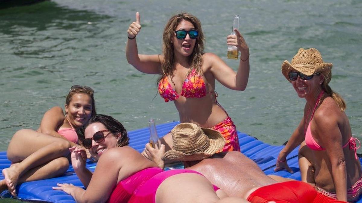 
Carla Alvarado, center with hands up, enjoys the water on the Nixon Beach sandbar off of Key Biscayne on Sunday.
