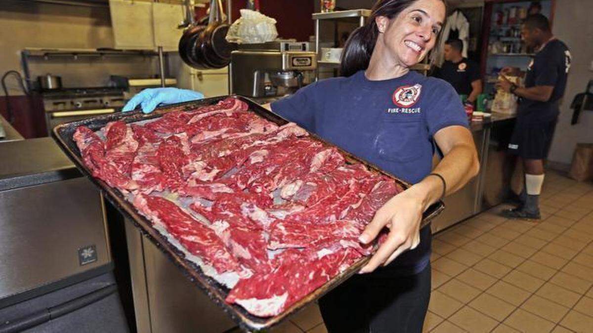 
City of Miami firefighters Anna Fiorenza carries the steaks to the grill as she prepares dinner at Fire Station #6, Feb. 10, 2015. Food and cooking, it has become a huge part of the culture at firehouses. With firehouse chefs competing in cooking competitions and opening up restaurants.
