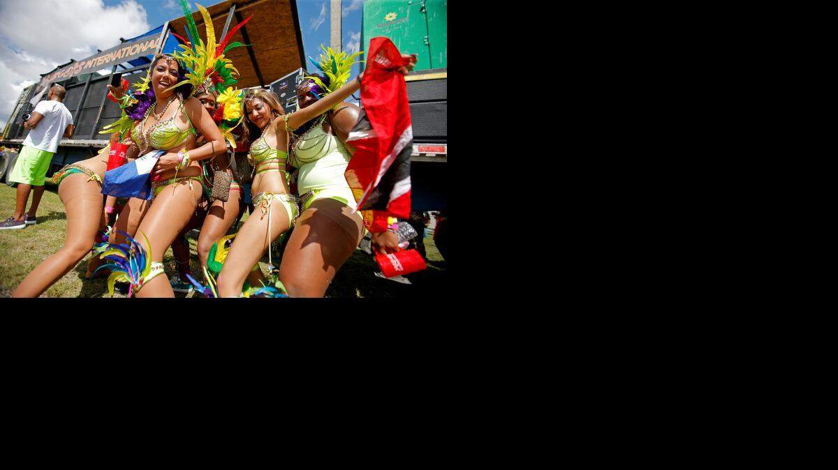 
Miami Broward One Carnival participants dance to music in front of the Mascots International Mas Band trailer at the Miami-Dade County Fair and Expo grounds. A masquerader was struck and killed by the trailer during the parade on Sunday, Oct. 12, 2014.
