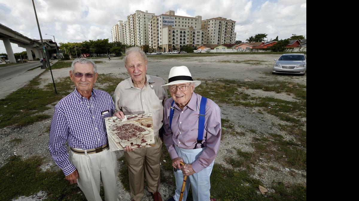 
Howard Katzen, S. Ronald Pallot and Norton Pallot, partners who owned the Norton Tire Company, return to the site of their Brownsville headquarters. The vacant lot was never rebuilt after rioters burned down their facility on the southwest corner of 54th Street and Northwest 27th Avenue. The photo in hand shows the destroyed building.
